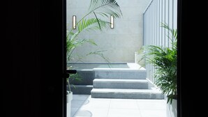 A modern building entrance with a concrete wall, a set of stairs, and two potted plants.