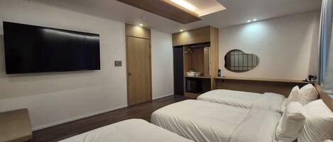 A hotel room with a flat-screen TV, a wardrobe, a mirror, and two beds.