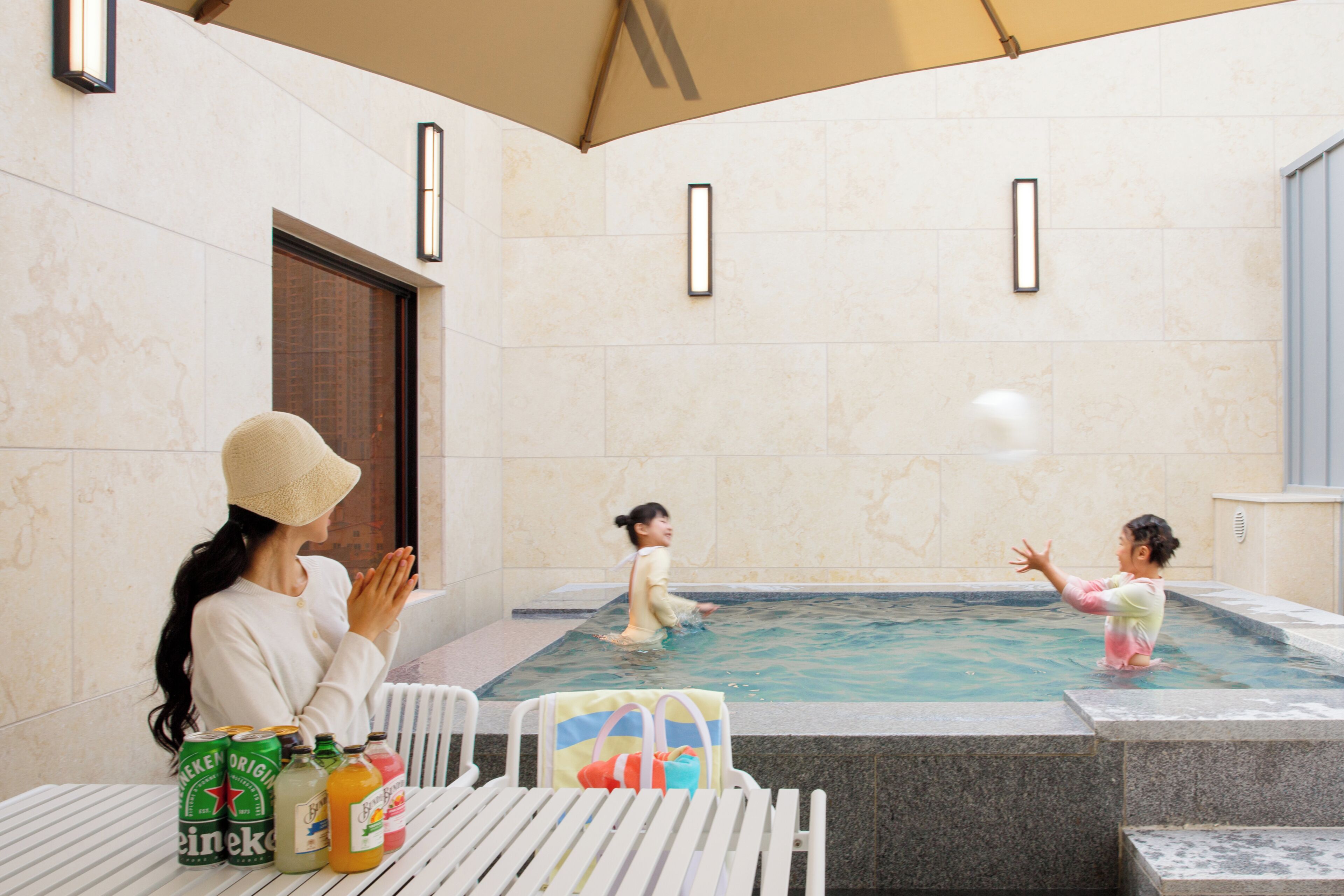 A pool area with tiled walls, a table with beverages, and lounge chairs.