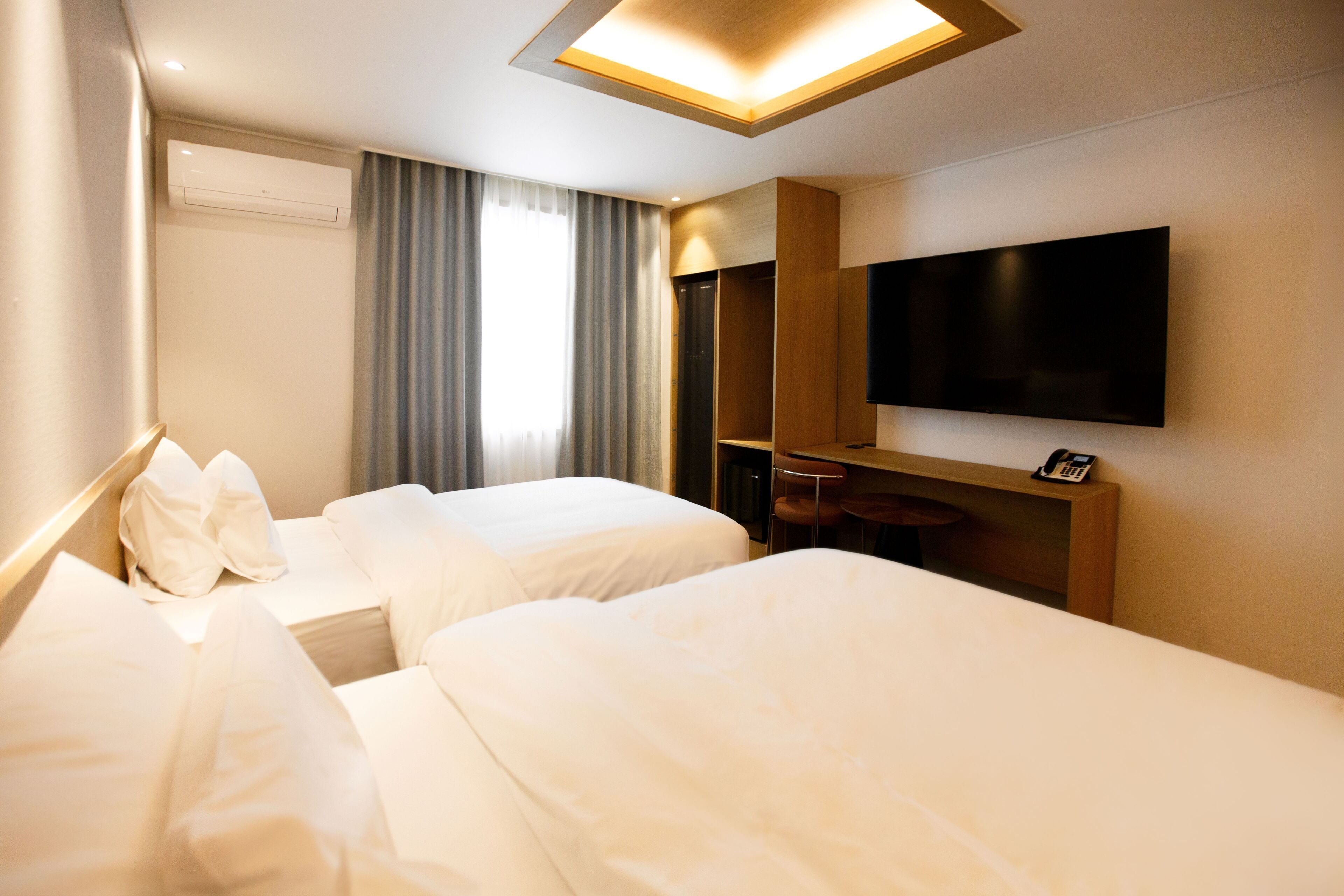 Habitación de hotel con dos camas, televisión y escritorio con silla.