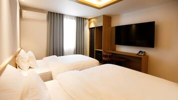 Habitación de hotel con dos camas, televisión y escritorio con silla.