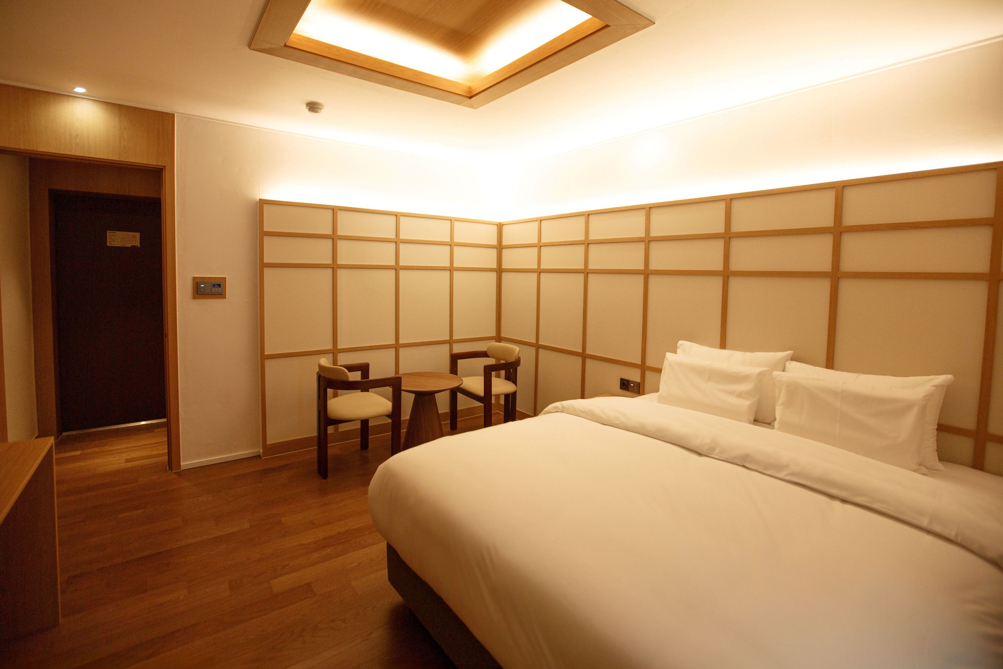 A hotel room with a bed, a desk, and a seating area with chairs.