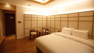 A hotel room with a bed, a desk, and a seating area with chairs.