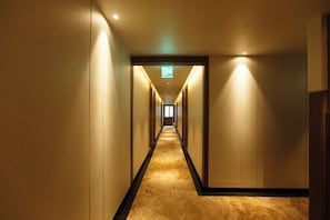 A long, narrow hotel corridor with a carpeted floor and walls on either side.