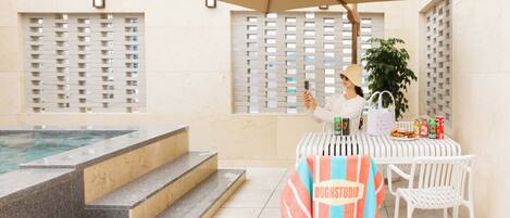 A poolside area with a table, chairs, and a person taking a photo.