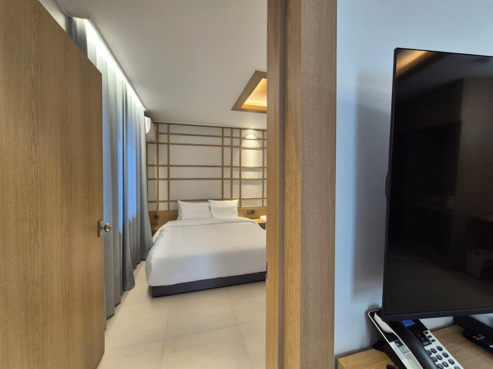 Una habitación de hotel con cama, televisión, escritorio con teléfono y armario.