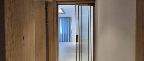 A hallway with wooden walls and a sliding glass door leading to a room.