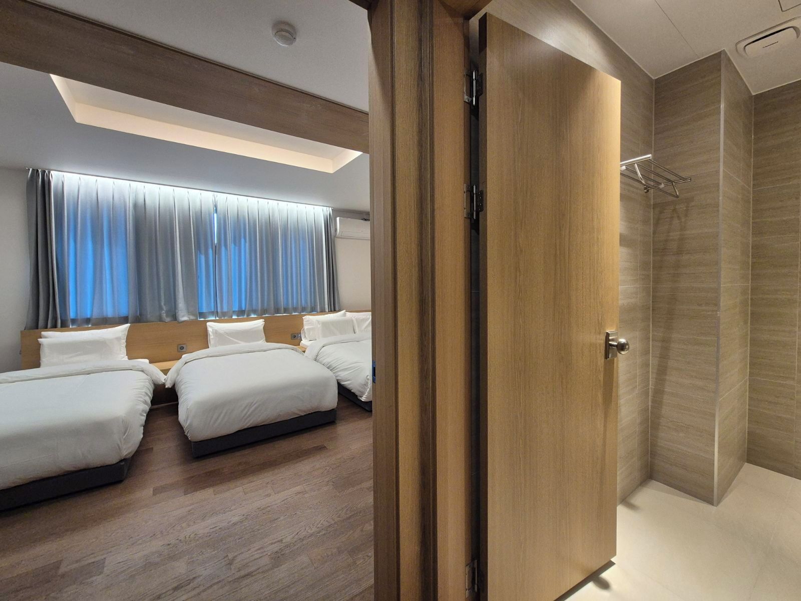Habitación de hotel con diseño moderno, que incluye una cama grande, zona de ducha y vista al cielo a través de la ventana.