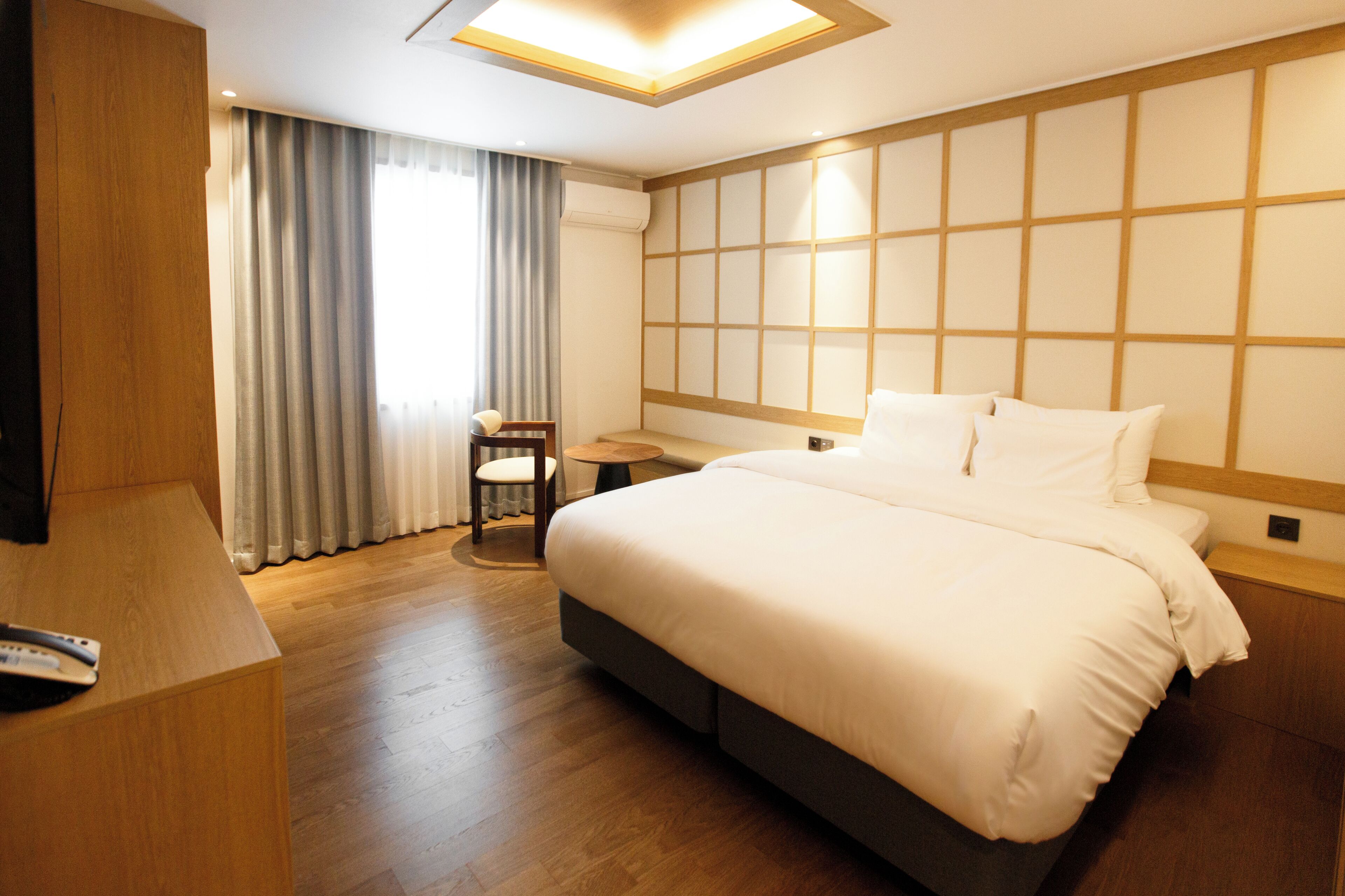 Habitación de hotel con una cama grande, un escritorio, una silla y vistas al exterior a través de la ventana.