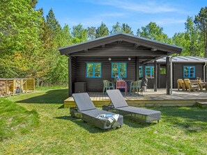 Une cabane en bois dotée d’une terrasse, d’un espace salon extérieur et d’un coin barbecue.