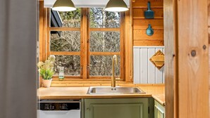 Een keuken met houten kasten, een roestvrijstalen spoelbak en een raam met uitzicht op bomen.
