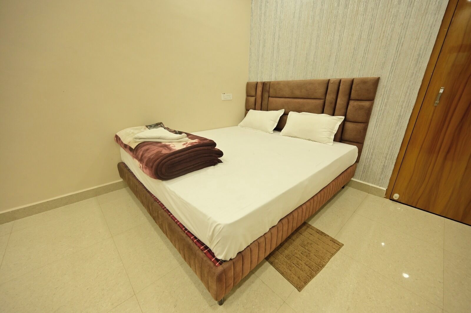 A neatly made bed with a brown headboard, a folded blanket, and two pillows.