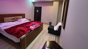 A bedroom with a bed, a ceiling fan, a door, and a small table. - The Palace Inn hotel with in peaceful Lahore (Lahore)