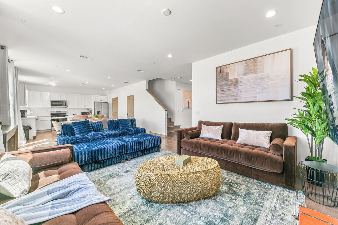 A modern living room with a sofa set, a coffee table, and a large painting on the wall.