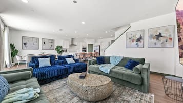 A modern living room with a sofa set, a round coffee table, and artwork on the walls.