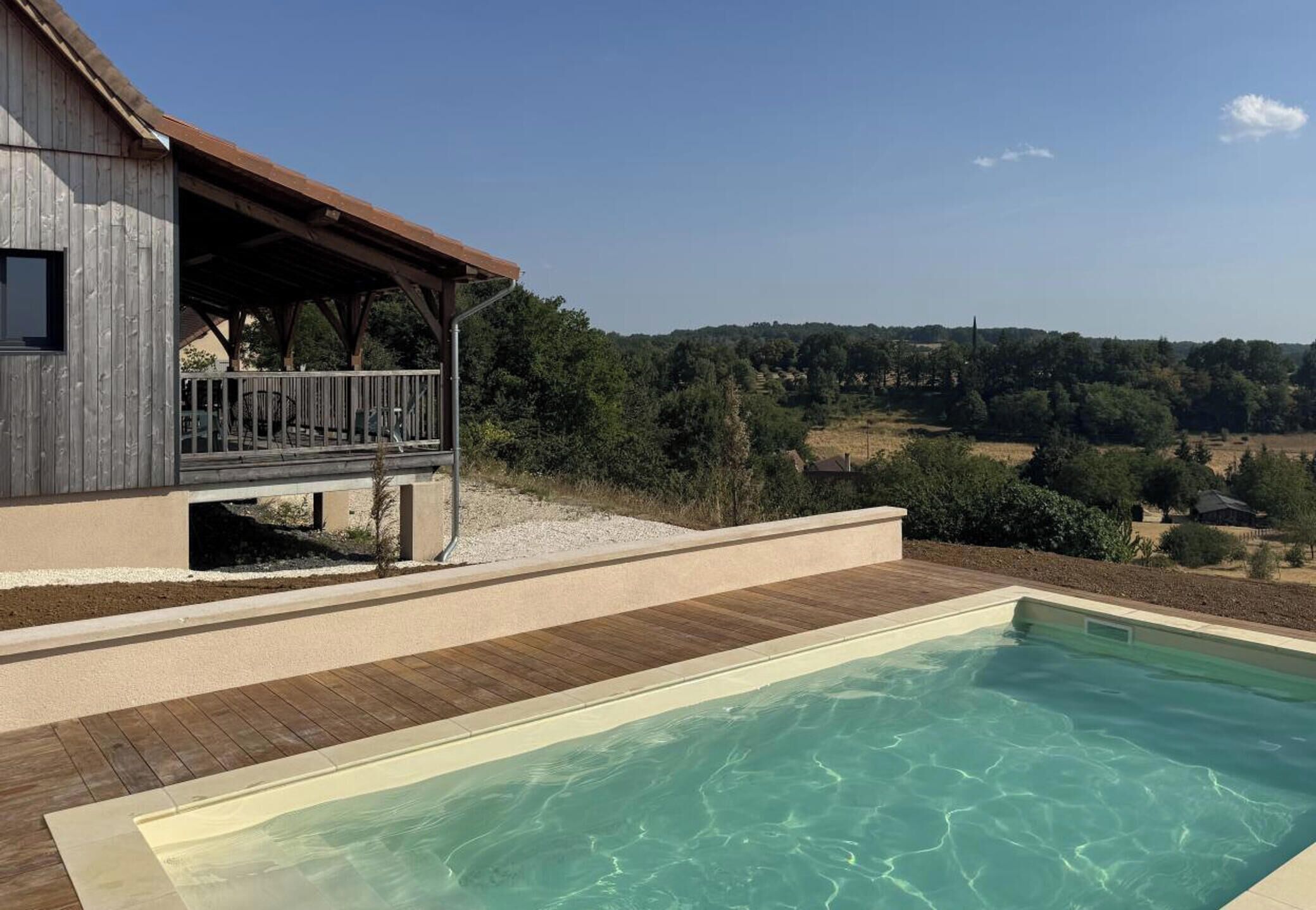 Ein Poolbereich mit Holzterrasse und Blick auf eine ländliche Landschaft.