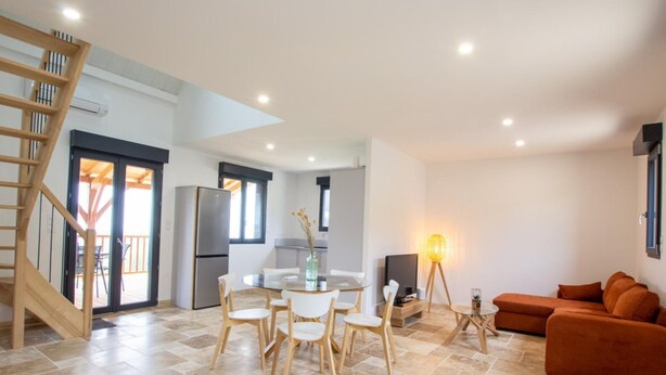 A modern living space with a dining area, a sofa, a TV, and a staircase. - Single-storey house, pets allowed - 2 guests (Preyssac-d'Excideuil)