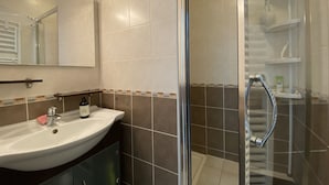 Ein Badezimmer mit Waschbecken, Spiegel und Duschbereich.