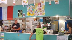 Una zona de bar con taburetes, una barra y varios objetos en estanterías.