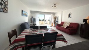 En matplats med ett bord dukat för två personer, en röd soffa, en tv och utsikt mot omgivningen.