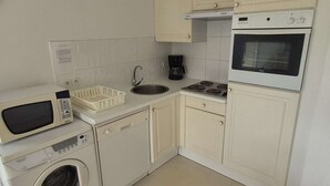 A compact kitchen with a microwave, washing machine, sink, coffee maker, and oven. - Calm apartment with parking - 4 guests (Cucq-Stella Plage)