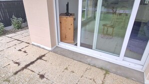 A building entrance with a wooden cabinet, a door, and a glass door leading to a patio area. - Calm apartment with parking - 4 guests (Cucq-Stella Plage)
