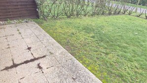 A concrete patio with a stone border, a wooden fence, and a grassy lawn. - Calm apartment with parking - 4 guests (Cucq-Stella Plage)