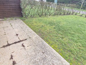 A concrete patio with a stone border, a wooden fence, and a grassy lawn. - Calm apartment with parking - 4 guests (Cucq-Stella Plage)