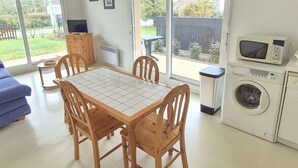 A modern kitchen with a dining table, chairs, a washing machine, and a microwave. - Calm apartment with parking - 4 guests (Cucq-Stella Plage)