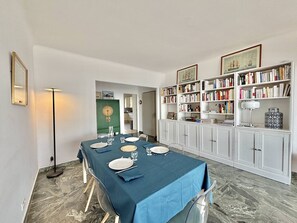 A dining area with a table set for four, a bookshelf, and a green cabinet. - Apartment with AC, sea view - 4 guests (Ajaccio)