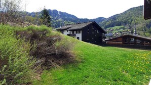 Paesaggio montano con un edificio dotato di tetto spiovente e struttura in legno con balcone.