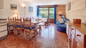 Una stanza accogliente con un tavolo da pranzo, sedie, un divano, una TV e una finestra con tende.