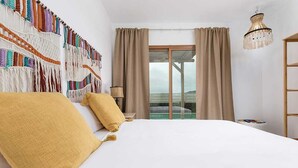 A bedroom with a bed, curtains, a chandelier, and a view through a window. - INLAJARES VILLA - 15M POOL IN PARADISE (Lajares)
