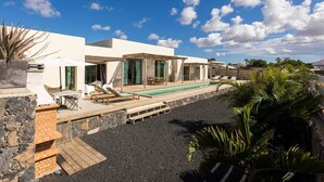 A modern villa with a pool, outdoor seating, and a stone wall. - INLAJARES VILLA - 15M POOL IN PARADISE (Lajares)