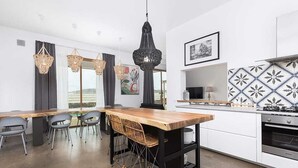 A modern kitchen with a wooden table, grey chairs, and hanging lights. - INLAJARES VILLA - 15M POOL IN PARADISE (Lajares)