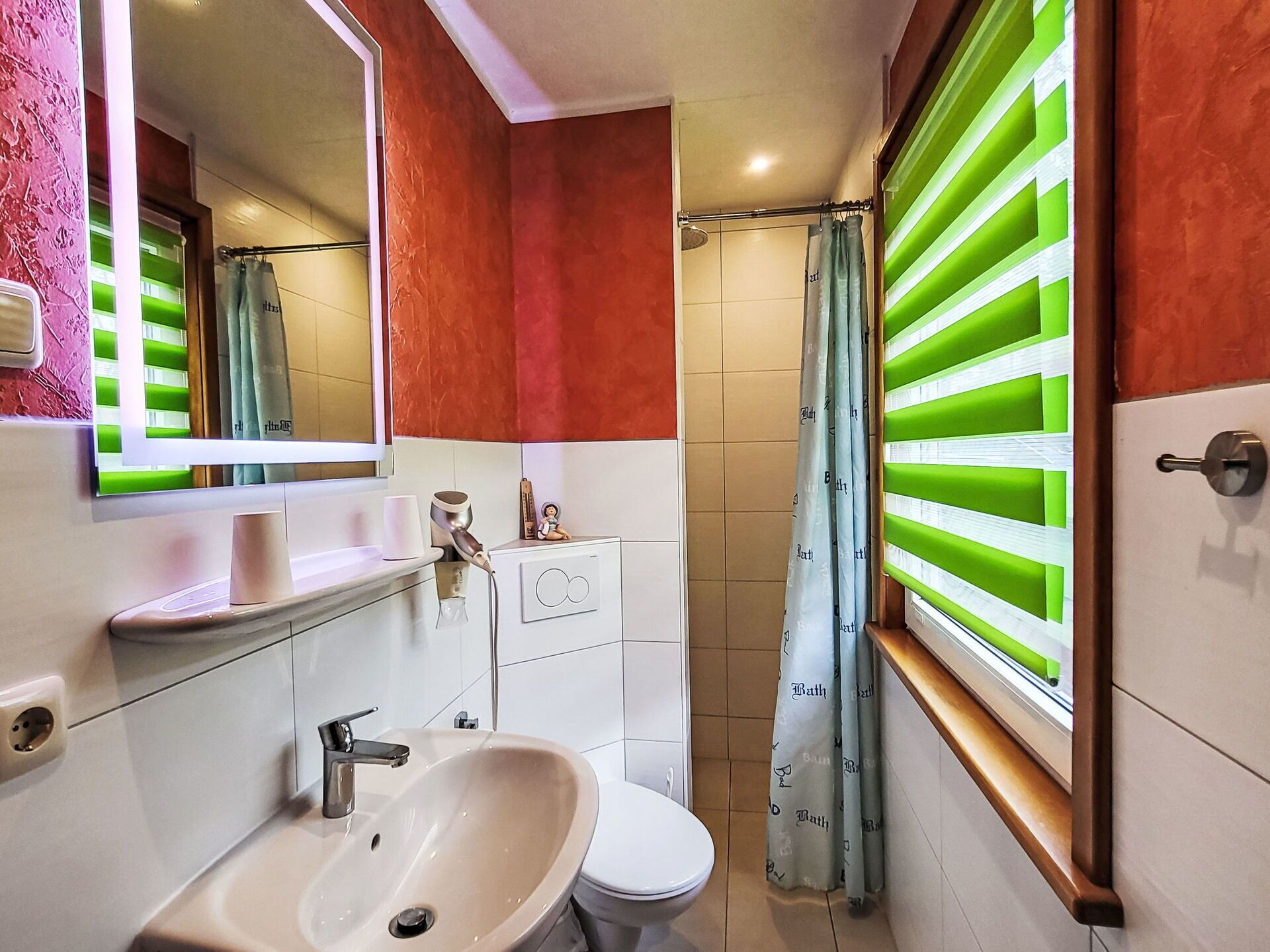 A bathroom with a sink, toilet, mirror, and shower.