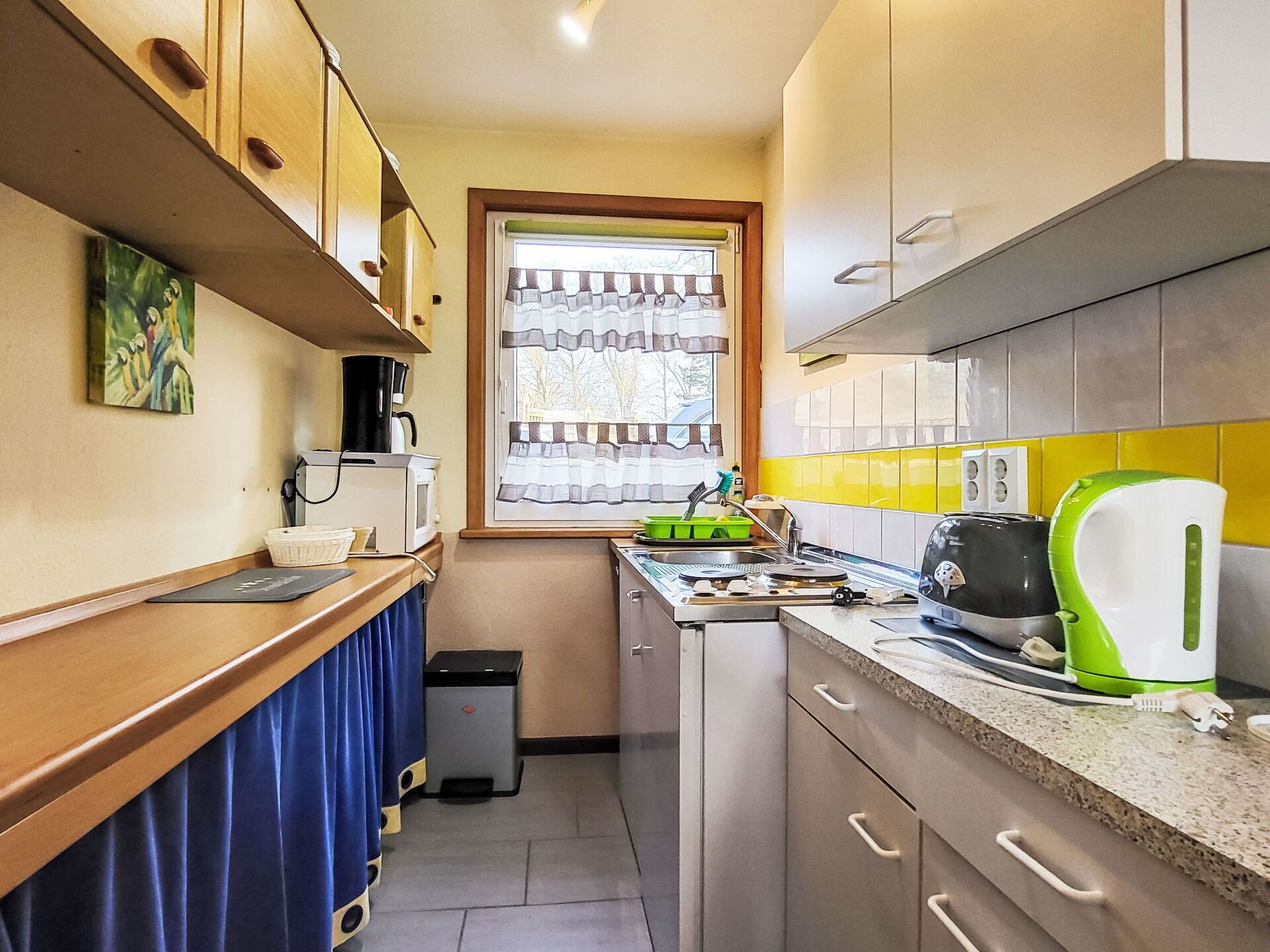 Cocina pequeña equipada con microondas, tetera y lavabo.