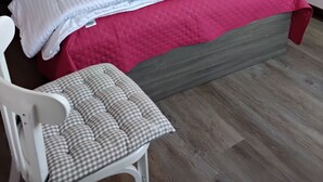 Een slaapkamer met een bed, een nachtkastje, een stoel en een aan de muur hangend schilderij.