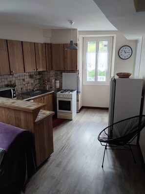 Eine Küche mit Holzschränken, einem Gasherd, einer Mikrowelle und einem Kühlschrank.