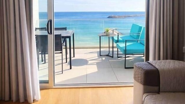 Ein Zimmer mit Balkon, einer Sitzecke, einem Tisch und Stühlen.