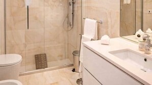 Ein modernes Badezimmer mit einer Duschkabine, einem weißen Waschbecken und einem großen Spiegel.