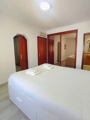 A hotel room with a large bed, a wardrobe, a mirror, and a ceiling light. - The Golden Hour Retreat (Alcochete)