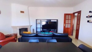Un salon avec un téléviseur, un canapé et une table à manger.