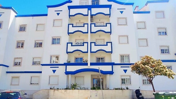 Un immeuble à plusieurs étages doté d’une façade symétrique, de balcons et d’une entrée centrale.