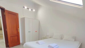 Une chambre avec un puits de lumière, une armoire, une table de chevet et un lit avec des serviettes.