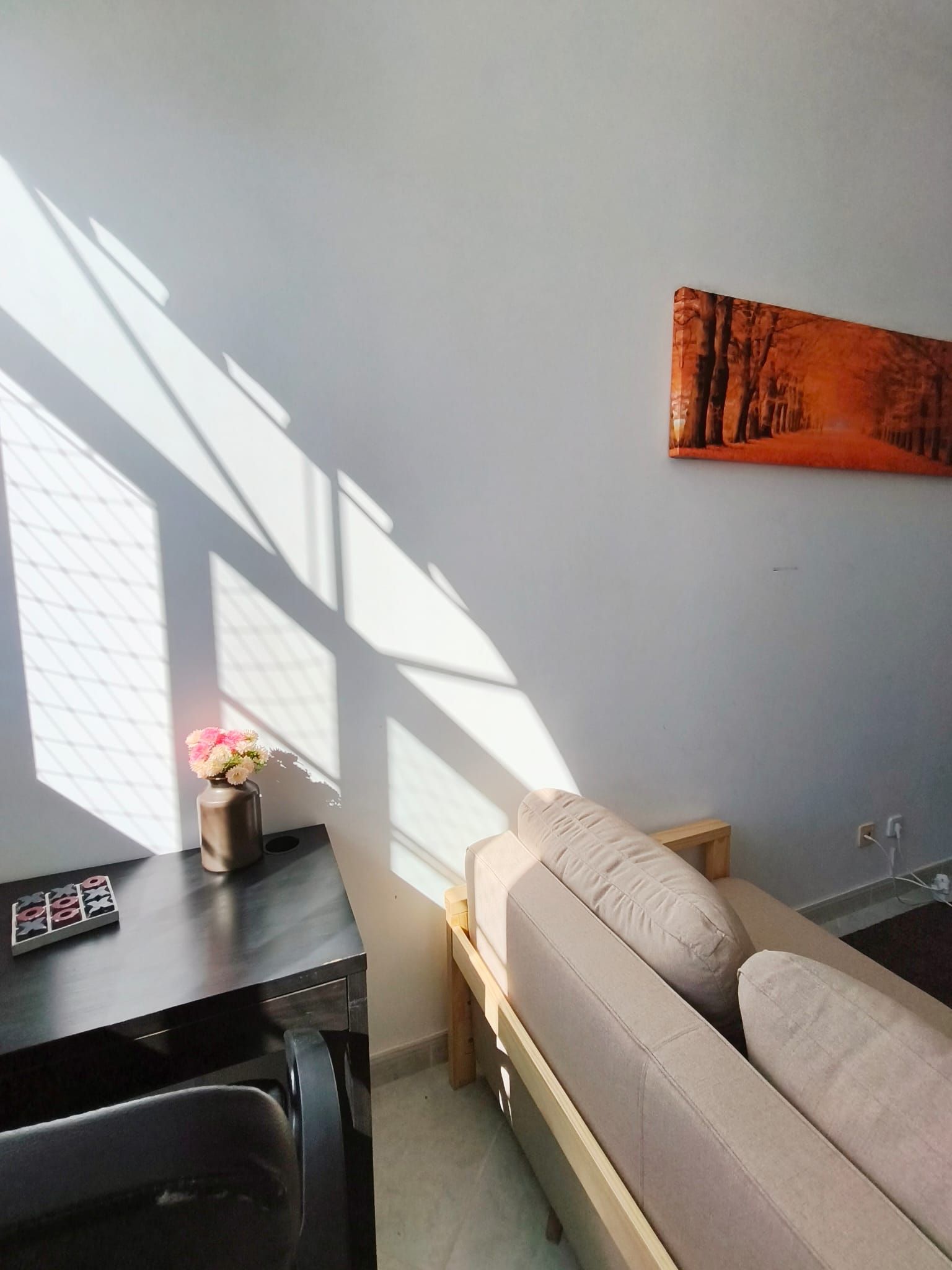 A modern living room with a sofa, a coffee table, and a painting on the wall.