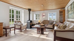 A spacious living room with a high ceiling, a fireplace, and large windows. - "Sigbritt" - 3.7km from the sea by Interhome (Nexø)