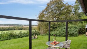 A patio with a table and chairs, a bottle of wine, and a view of a green landscape. - "Sigbritt" - 3.7km from the sea by Interhome (Nexø)