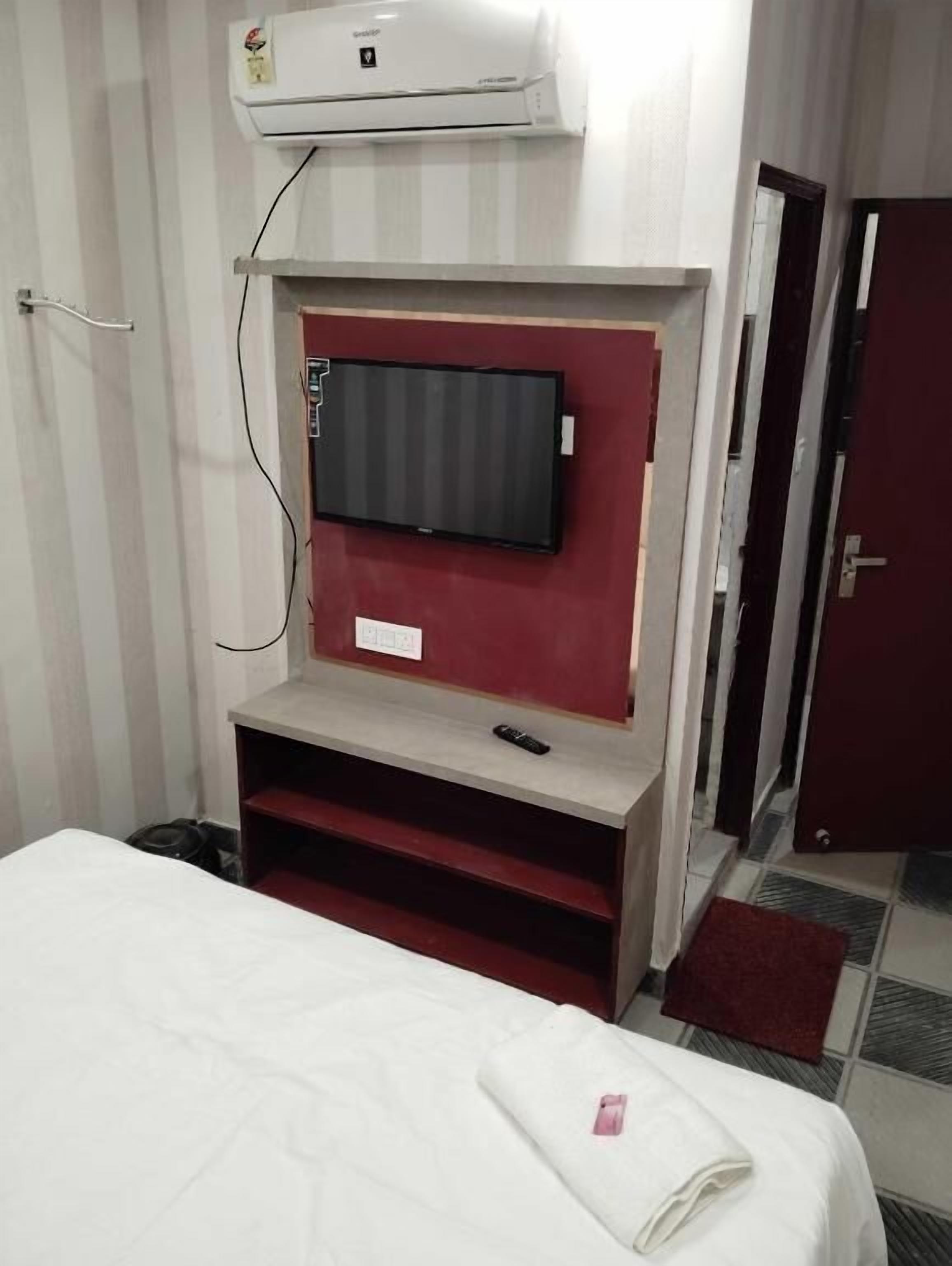 Une chambre d’hôtel équipée d’un lit, d’un téléviseur fixé au mur, d’une petite table et d’un appareil de climatisation.