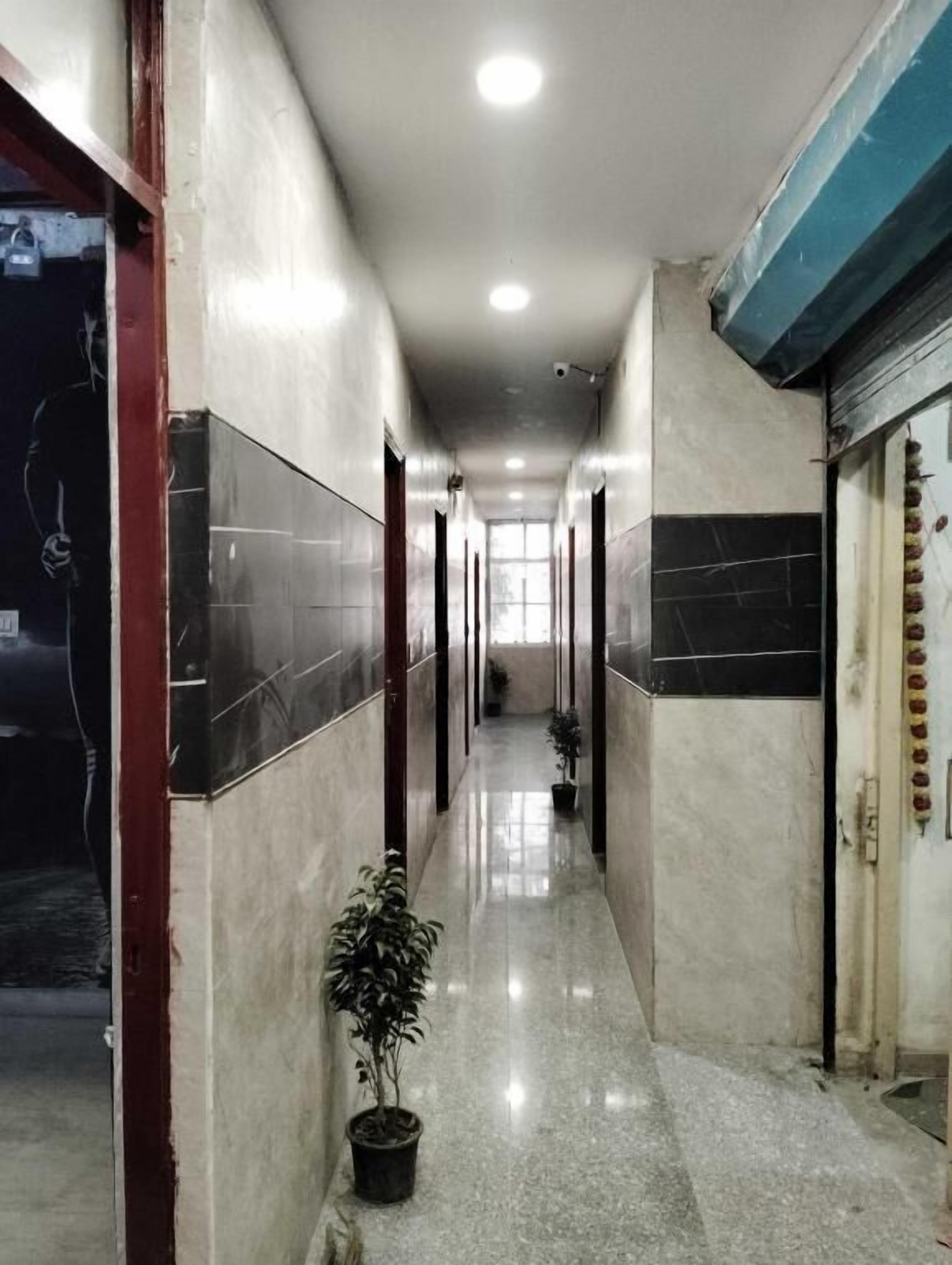 Un largo y estrecho pasillo con paredes de azulejos y piso pulido, que conduce a una puerta al final.